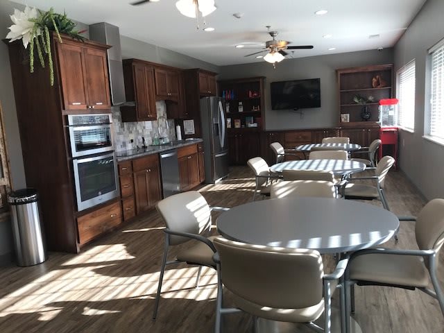A modern kitchen and dining area with wooden cabinets and multiple tables and chairs.