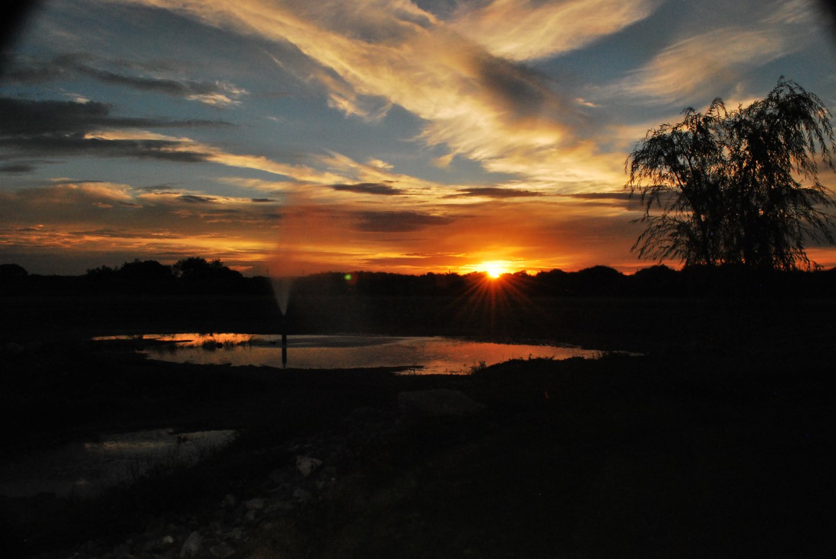 A serene sunset with vibrant colors reflecting over a calm water surface.