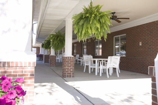 A serene outdoor porch area adorned with hanging plants and white furniture.