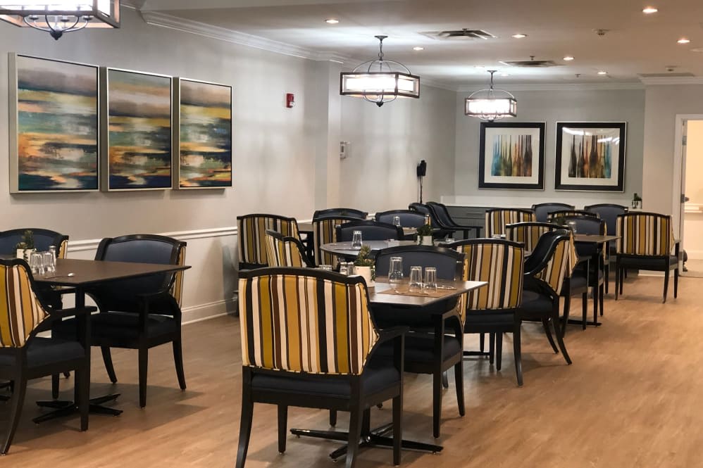 A modern dining area with striped chairs, tables, and decorative artwork on the walls.