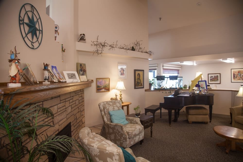 A cozy living room featuring a fireplace, armchair, and grand piano.