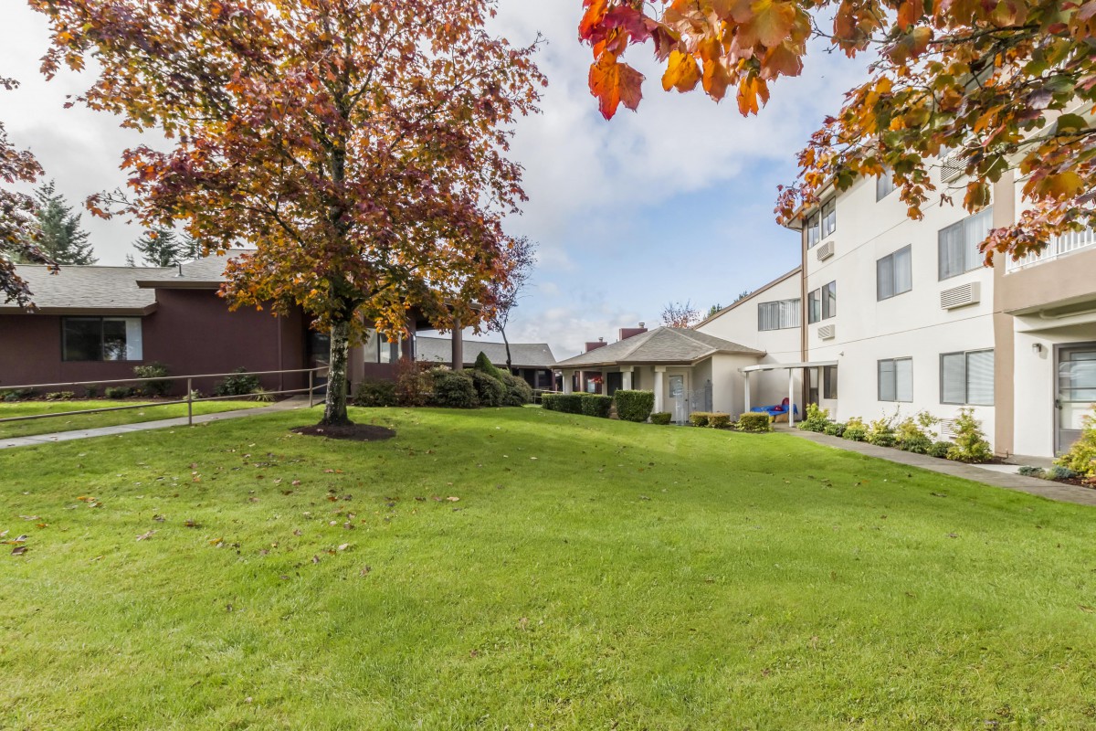 A pleasant view of an apartment complex with a well-maintained green lawn and trees.