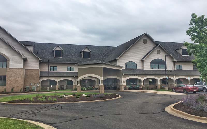 A large residential building with an arched entrance and a driveway under a cloudy sky.