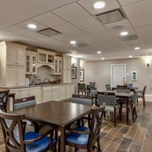 A cozy kitchen and dining area with multiple tables and chairs, well-lit and featuring modern cabinetry.