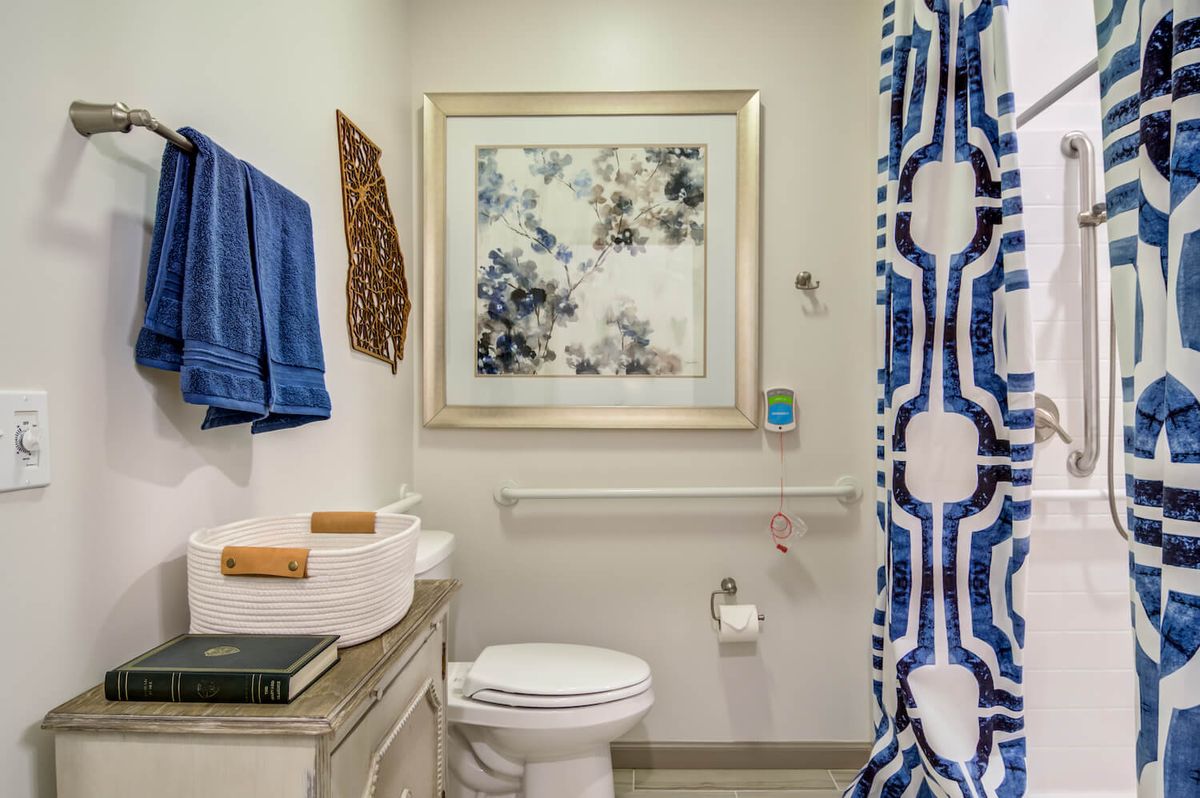 A neatly organized bathroom with blue accents and decorative artwork.