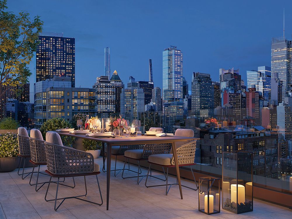 A beautifully set table on a rooftop overlooking a city skyline at dusk.