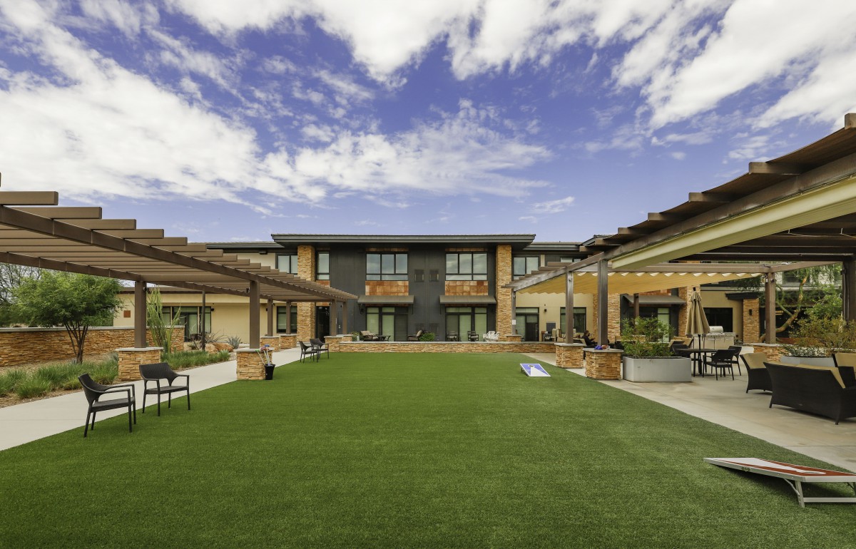 A modern building with a central courtyard and well-maintained lawn under a partly cloudy sky.