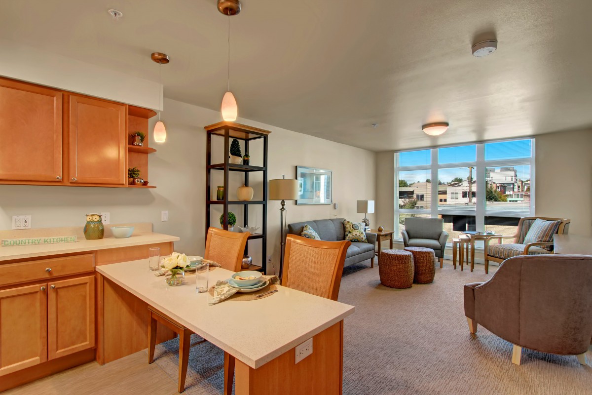 A modern open-concept apartment with a combined kitchen, dining, and living area, featuring contemporary furniture and ample natural light.
