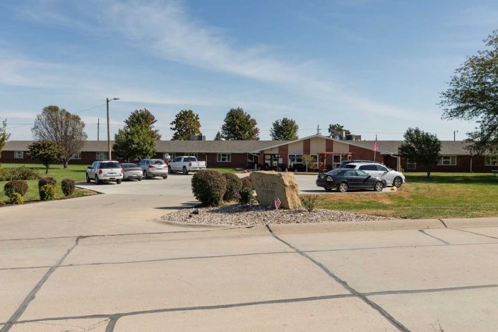 A parking lot in front of a single-story building with several parked cars on a clear day.