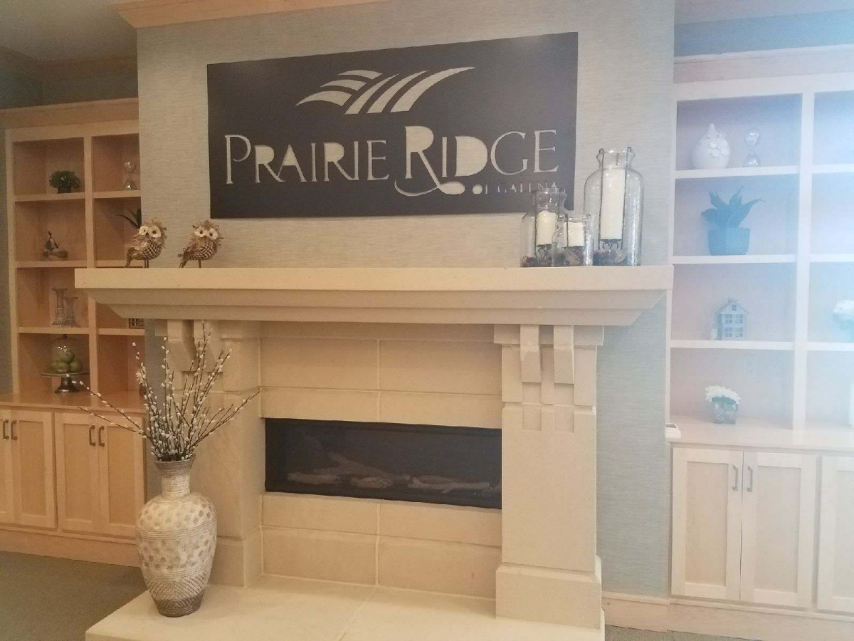 A cozy fireplace with a 'Prairie Ridge' sign above it, surrounded by decorative elements.