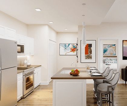 A modern kitchen featuring an island with bar stools, contemporary artwork, and sleek appliances.