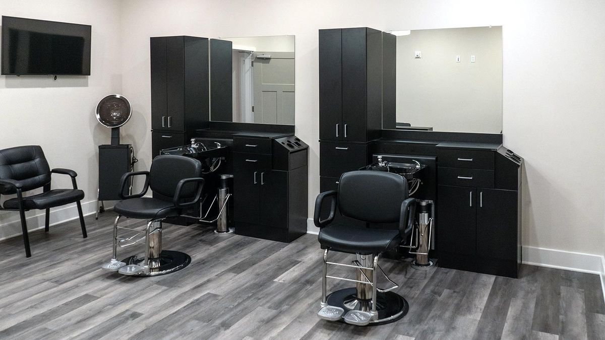 A modern barbershop interior with styling chairs and mirrors.