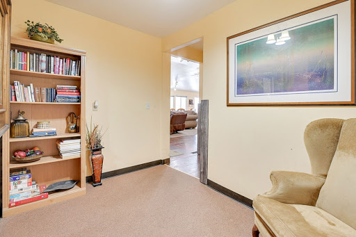A cozy interior hallway featuring a bookshelf and framed artwork, leading to a living area.
