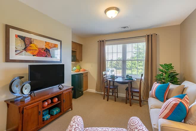 A cozy living room with a television, sofa, and a dining area by the window.