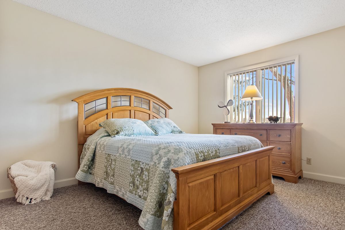 A cozy bedroom featuring a wooden bed frame, matching dresser, and a window letting in natural light.