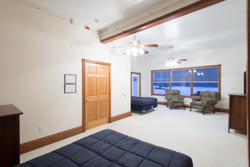 A spacious bedroom with two beds, cozy armchairs, and large windows providing ample natural light.