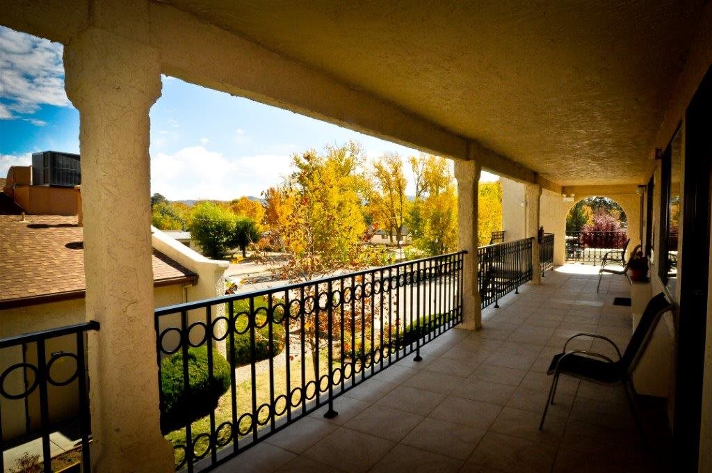 A spacious balcony overlooks a scenic view with autumn trees on a sunny day.
