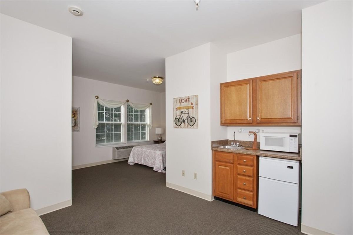 A cozy studio apartment featuring a kitchenette and a sleeping area.