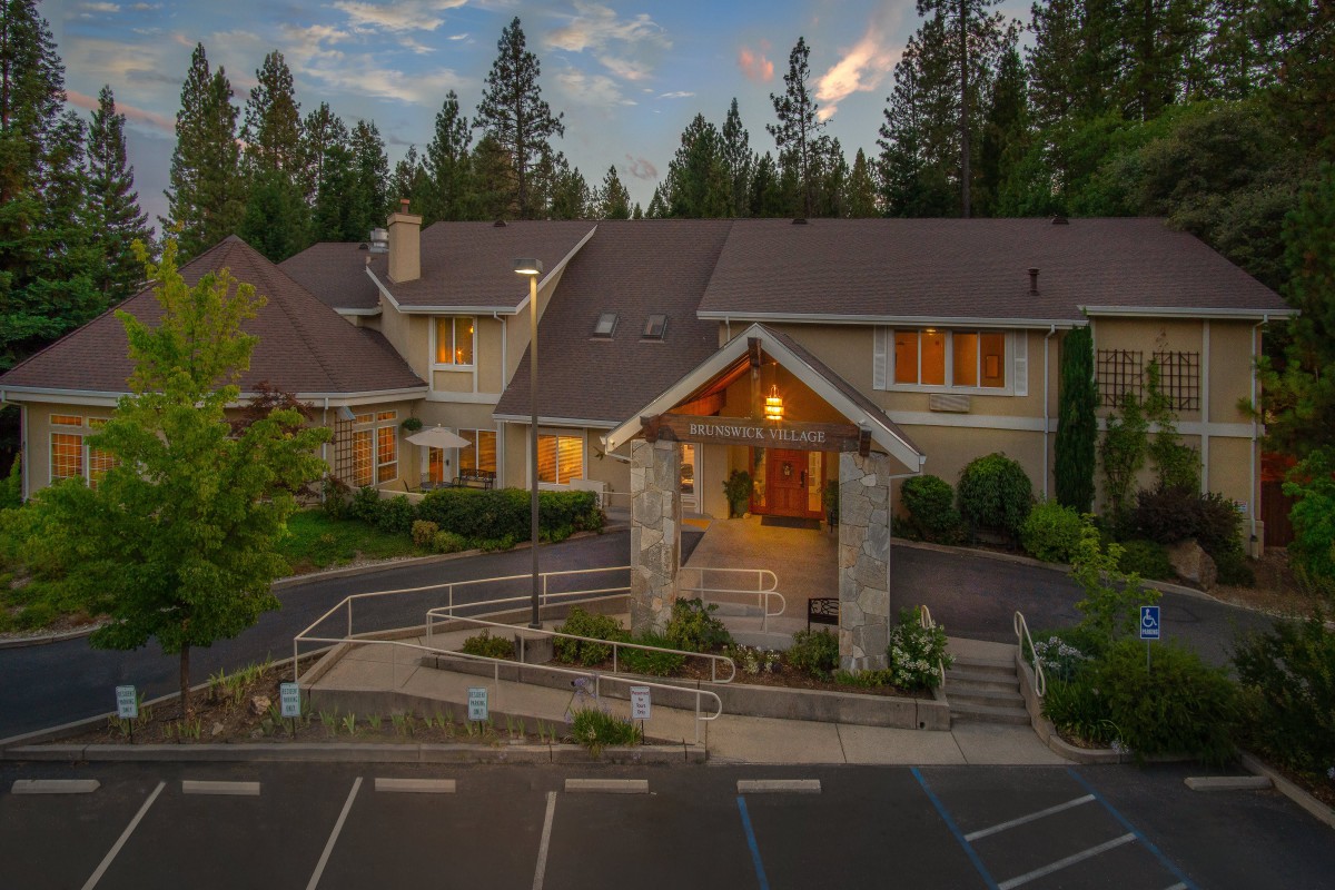 A large, inviting house surrounded by trees at dusk.