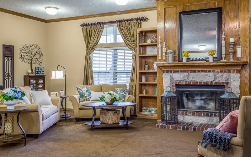 A cozy living room featuring a fireplace, bookshelf, and comfortable seating.