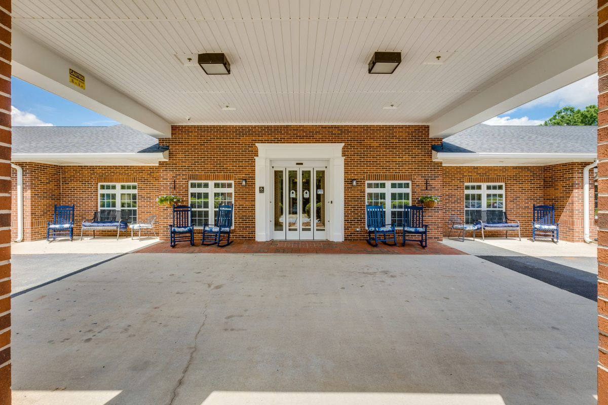 The image shows the entrance of a brick building with a covered walkway and benches on either side.