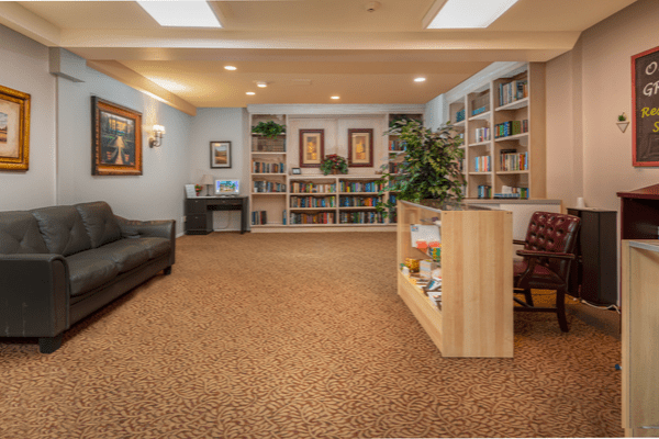 A cozy library room with bookshelves, seating, and decorative elements.