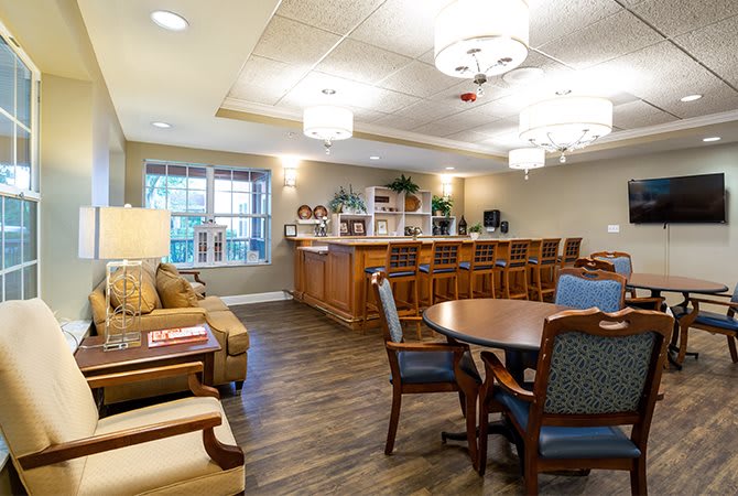 A cozy living area featuring a bar counter and comfortable seating, enhanced by stylish lighting fixtures.