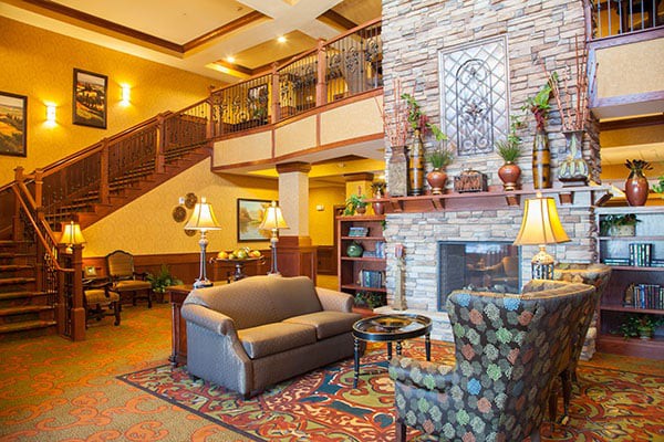 A cozy hotel lobby with a fireplace, comfortable seating, and a staircase.