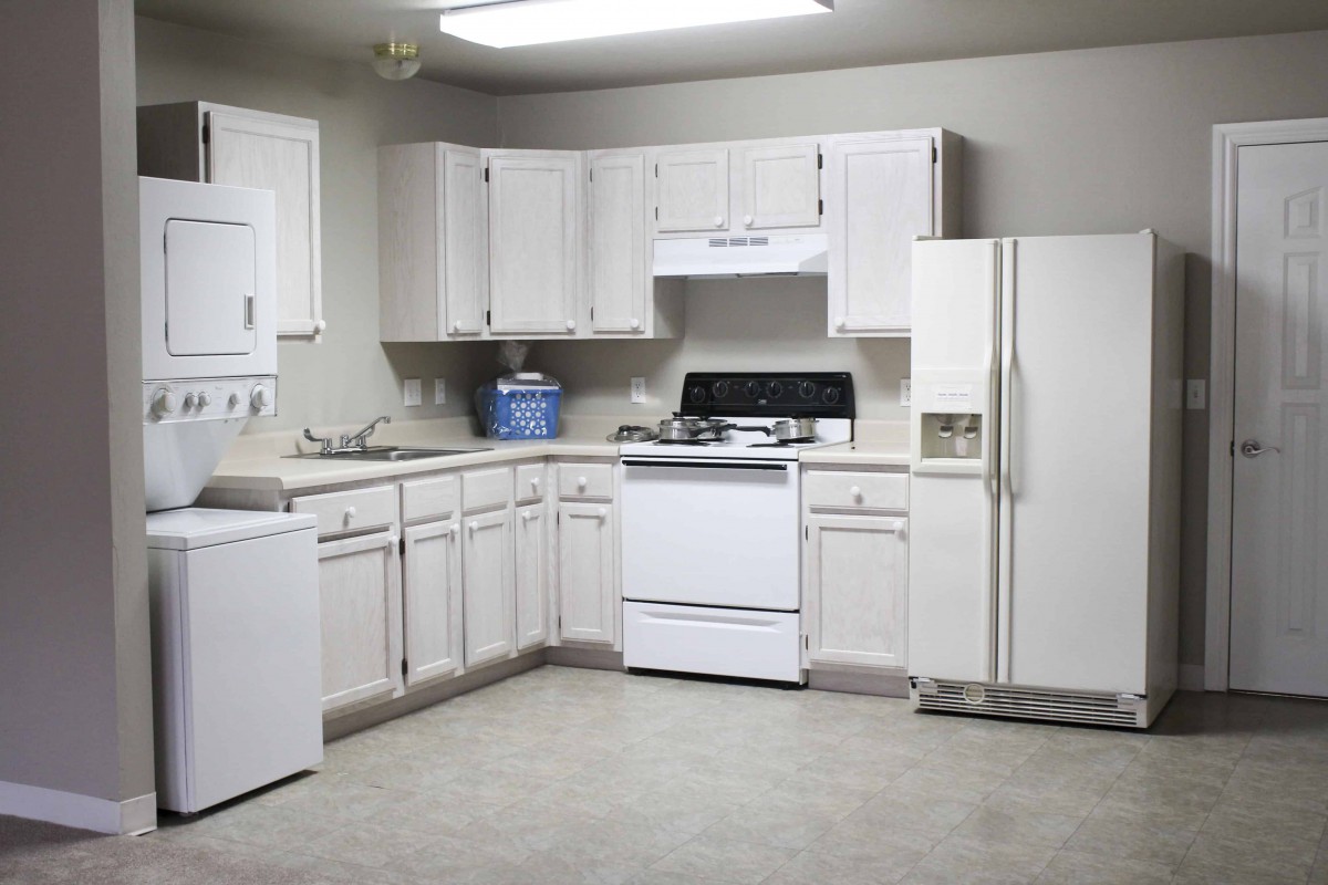 A clean and simple kitchen with white cabinets and standard appliances.