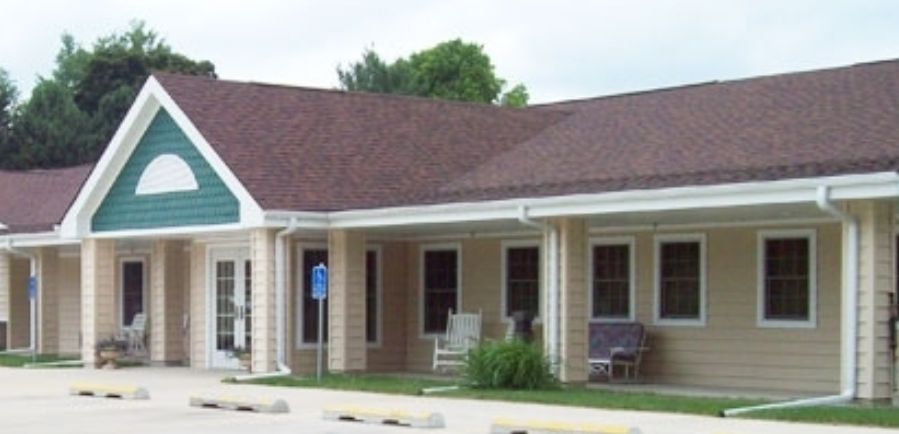 A suburban residential building with a porch and a sloped roof.