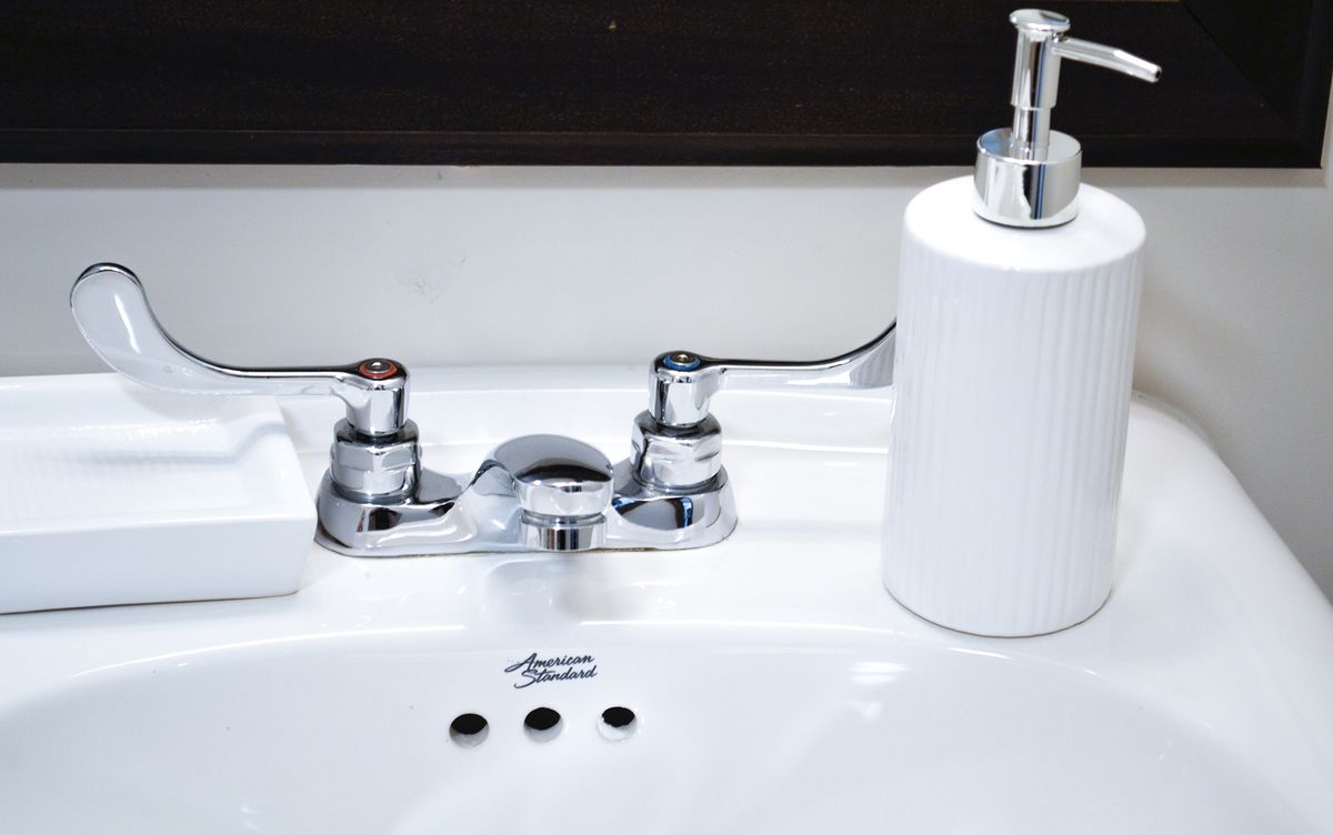 A clean bathroom sink with a chrome faucet and a white soap dispenser.