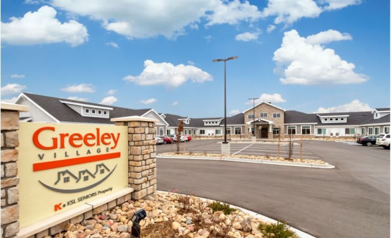 Entrance to a residential facility with clear skies and a well-maintained parking area.