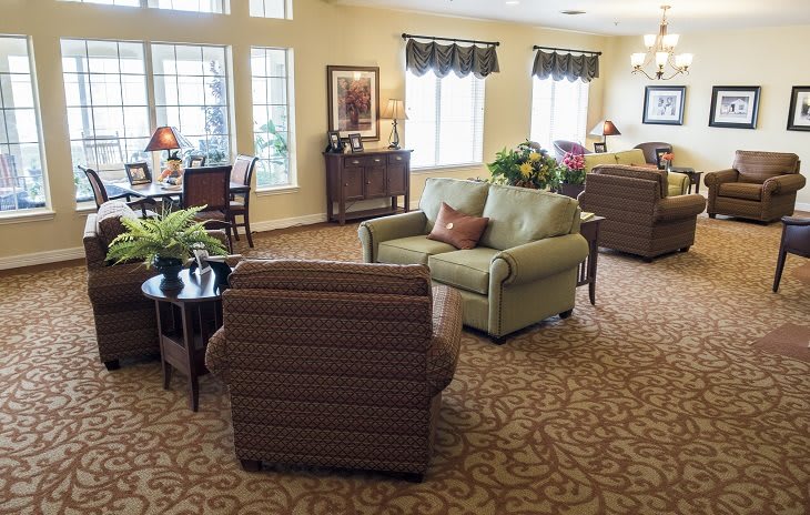 A cozy living room with sofas, armchairs, and large windows.