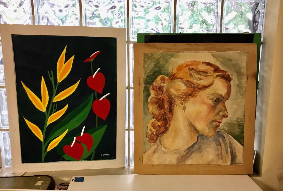 A display of two paintings featuring a floral design and a portrait.