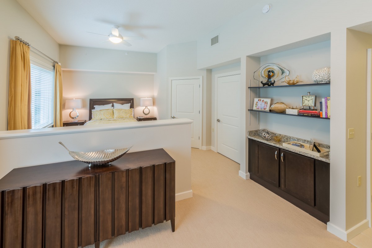 A modern bedroom with stylish decor featuring a bed, lamps, and shelving.