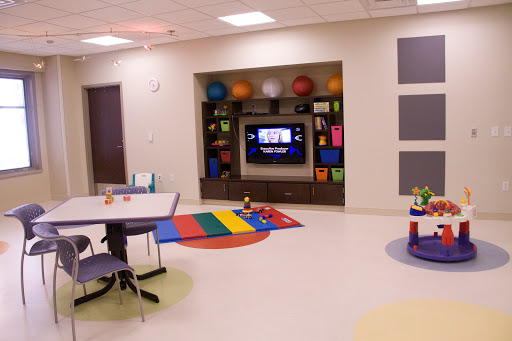 A vibrant playroom designed for children, featuring a TV, colorful rugs, and various exercise balls.