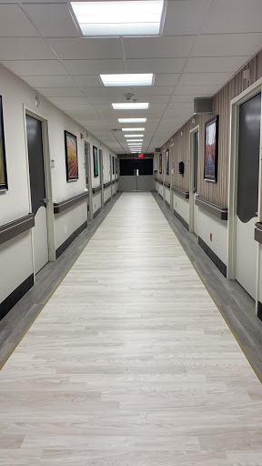 A well-lit corridor in a hospital, featuring white walls and modern flooring.