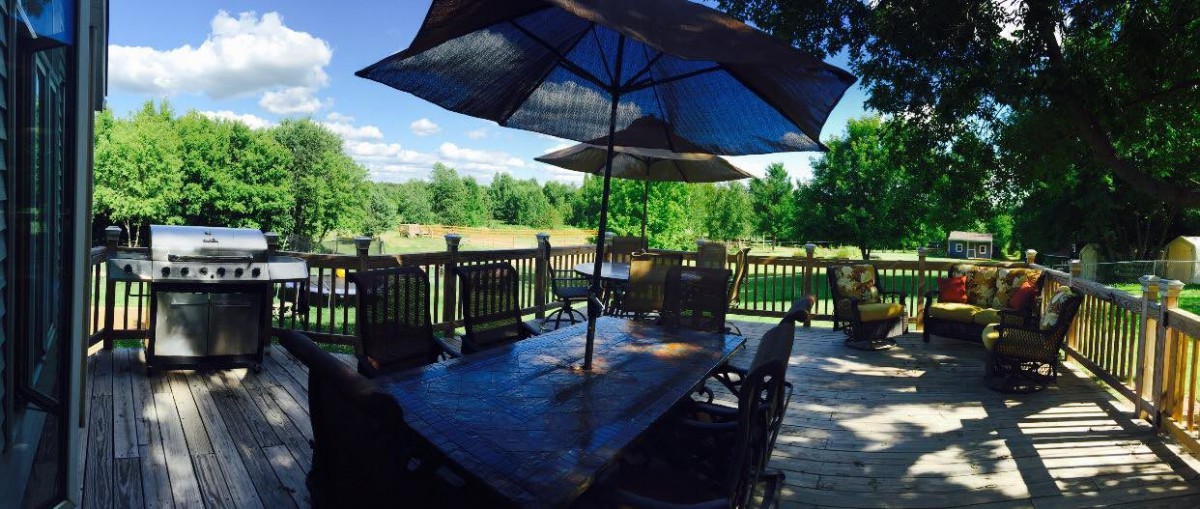 A scenic outdoor patio with a table, chairs, and large umbrellas overlooking lush greenery.