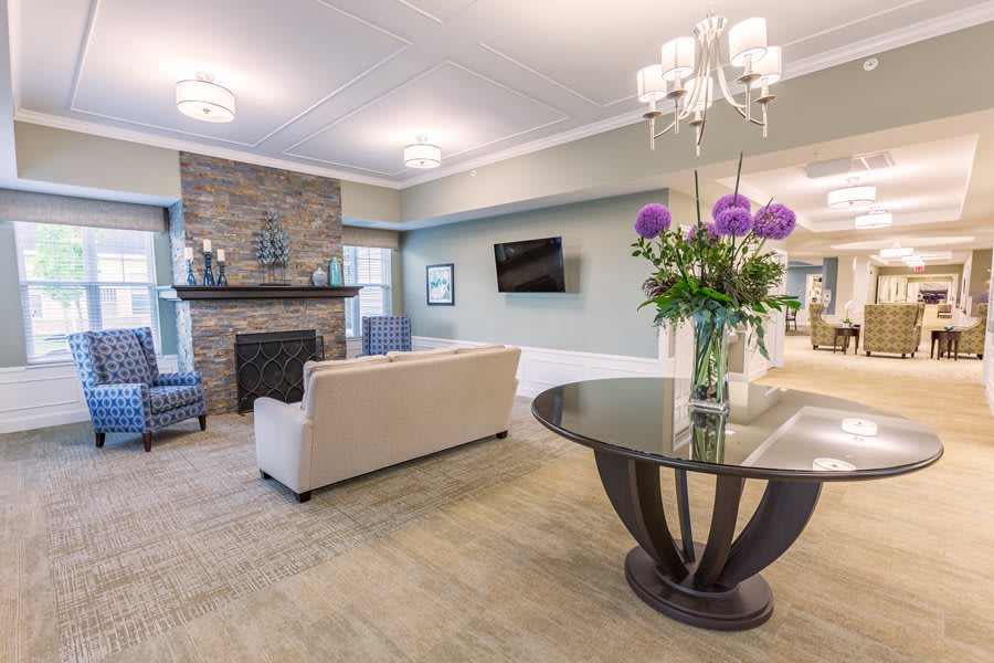 A modern living room with a cozy fireplace, comfortable seating, and a decorative table with flowers.