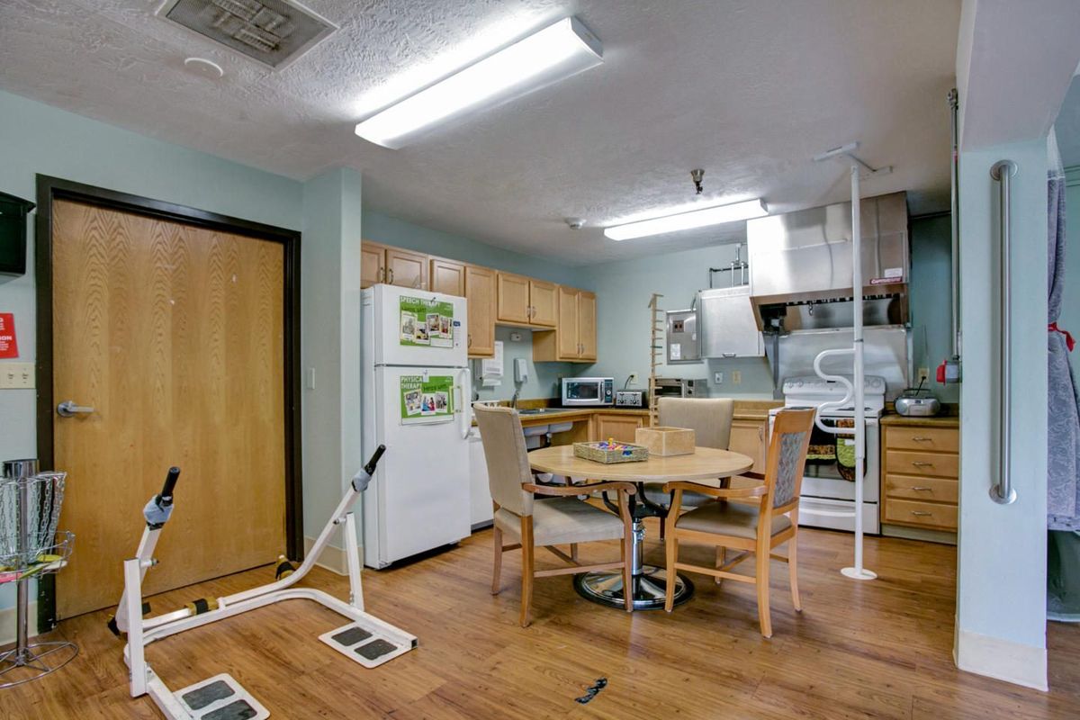 A kitchen and dining area with appliances and a round table surrounded by chairs.