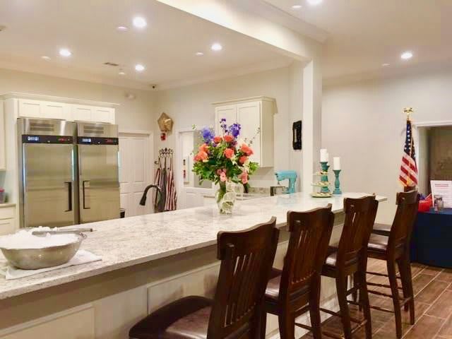 A modern kitchen with a marble counter, wooden stools, and a bouquet of colorful flowers.