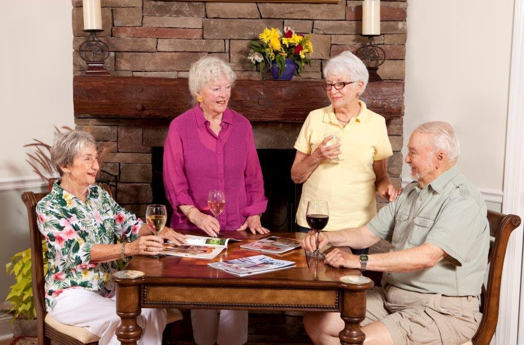 A group of seniors enjoying each other's company with drinks around a table.