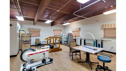 A spacious physical therapy room equipped with various rehabilitative devices and exercise equipment.