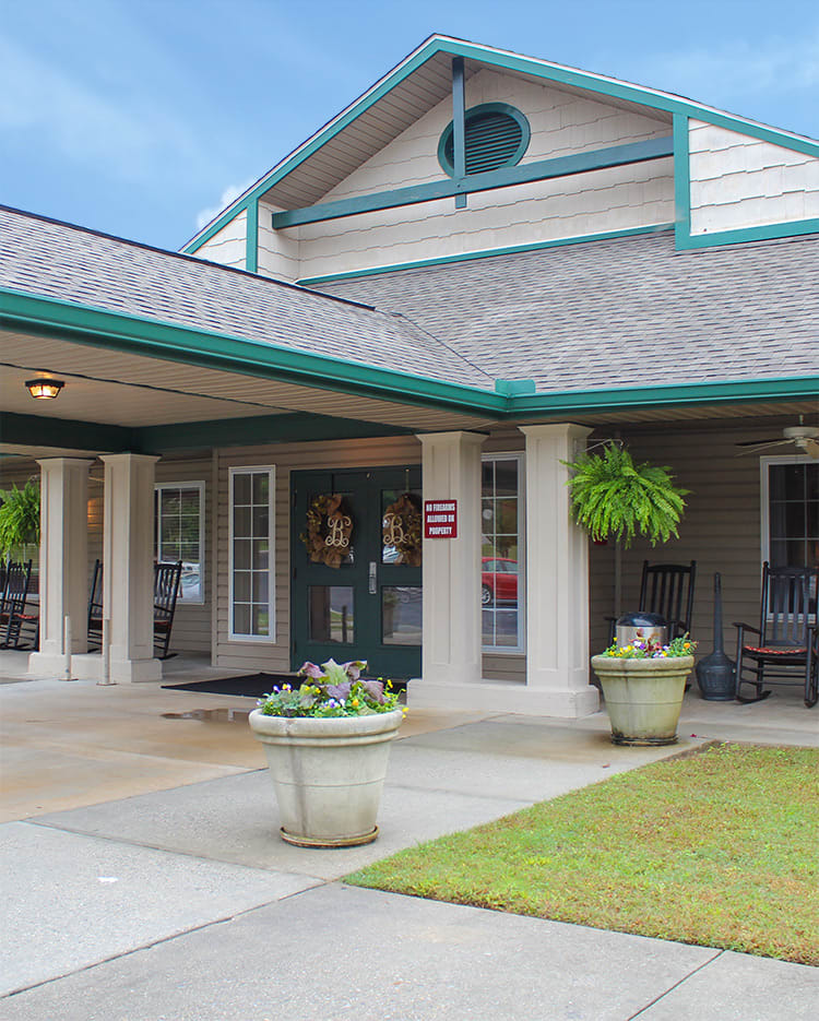 A welcoming building entrance with a porch and decorative plants.