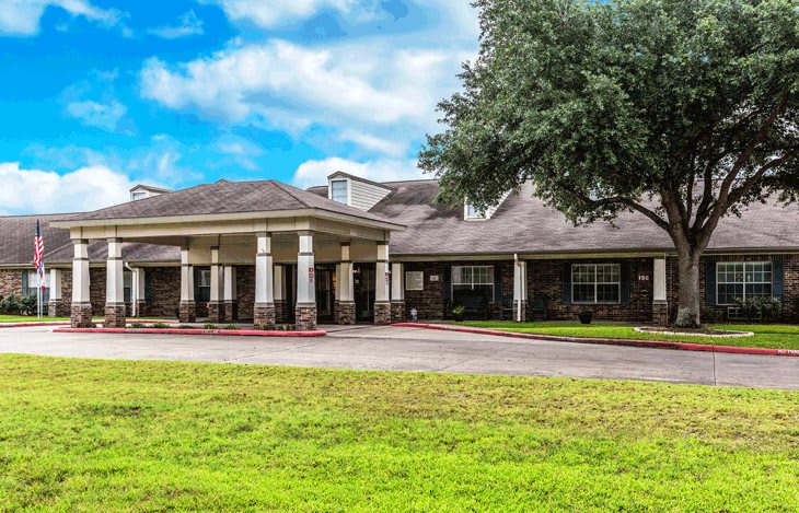 A residential building with a grassy lawn and a cloudy sky.