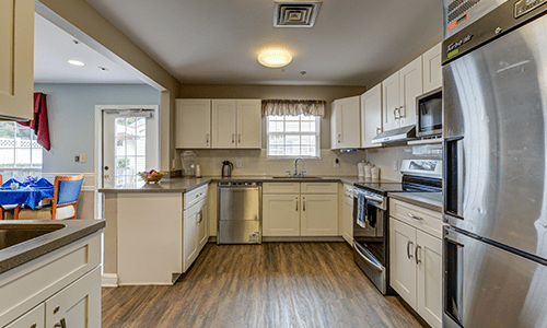 A modern kitchen featuring white cabinets, stainless steel appliances, and hardwood flooring.