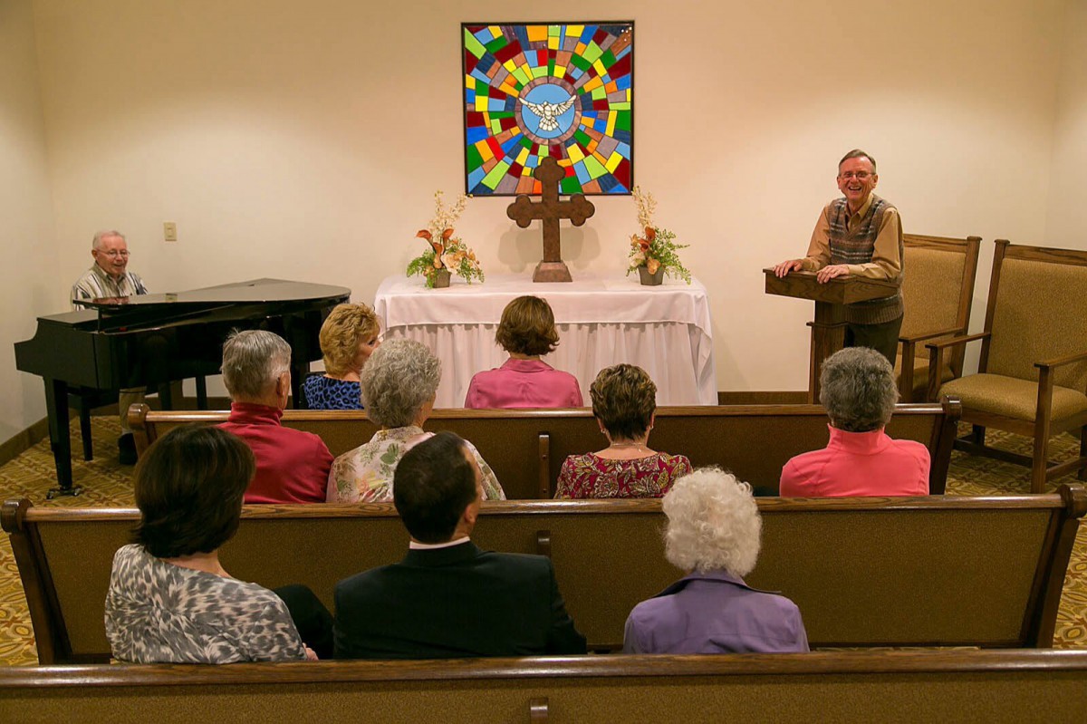 A church service in progress with congregants seated and a speaker at the podium.
