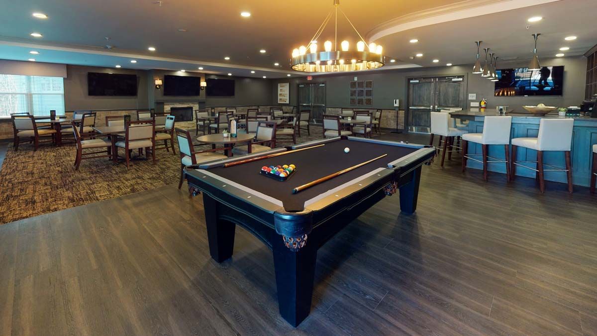 A luxurious entertainment room featuring a billiards table and elegant seating under a grand chandelier.