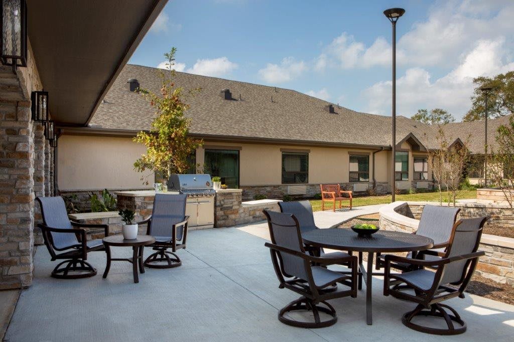 A sunny outdoor patio with tables and chairs in front of a building.