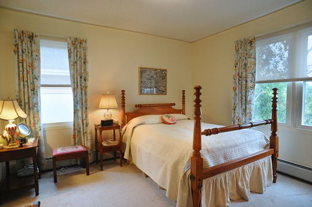 A cozy bedroom with traditional decor featuring a four-poster bed and warm lighting.